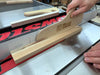 Wooden push stick being used on a table saw with a visible brand logo.