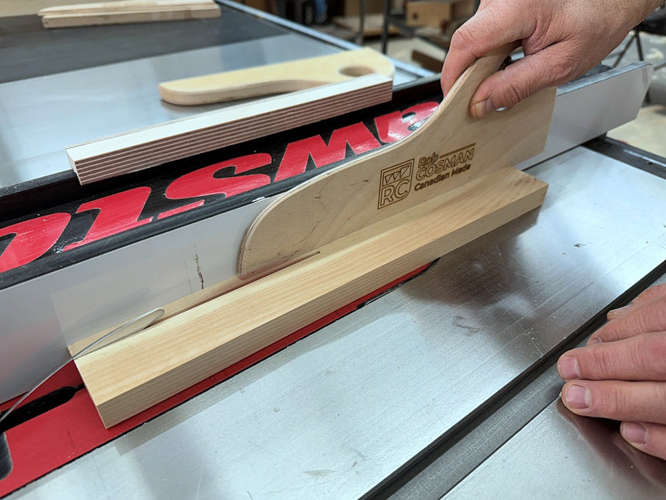 Wooden push stick being used on a table saw with a visible brand logo.