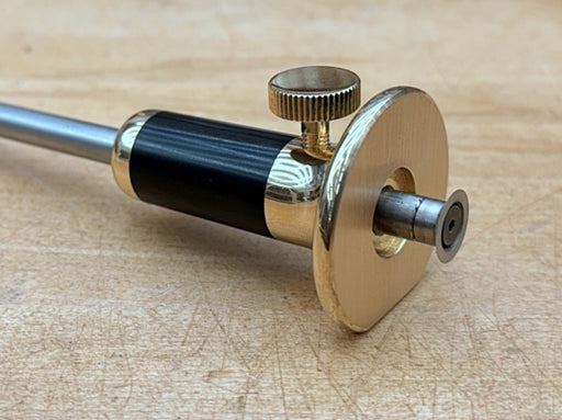 Rob Cosman's woodowrking marking gauge with brass and black finish on a wooden surface