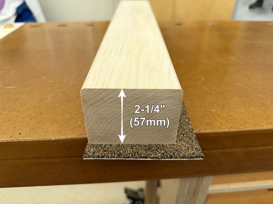 A hard maple vise jaw on a workbench with a white dimension arrow and text indicating a thickness of 2-1/4 inches (57mm).